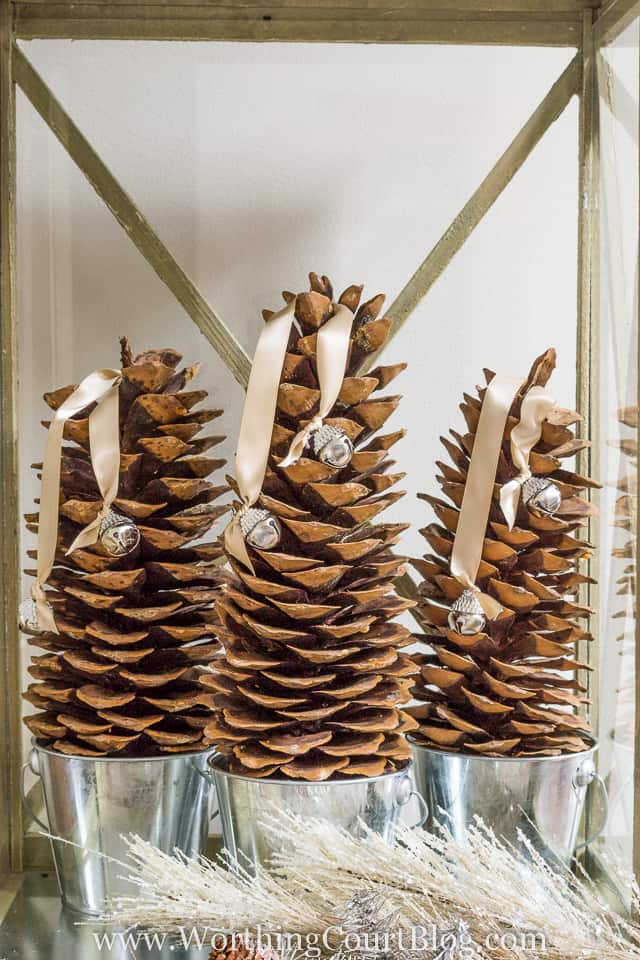 Three pine cones in silver buckets inside the lantern.