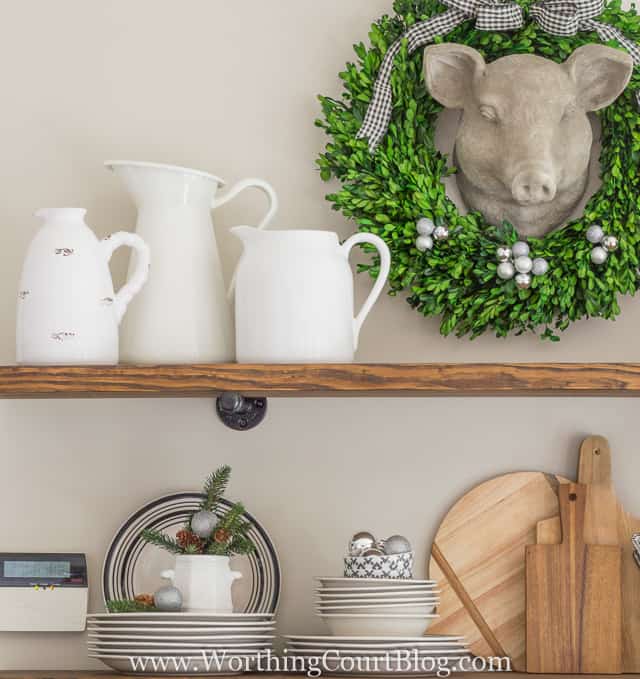 Rustic Farmhouse Kitchen Shelves Decorated For Christmas with white pitches, plates and wooden cutting boards.