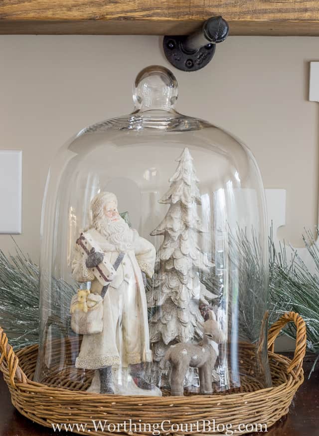A glass cloche with a small deer and Santa and Christmas tree.