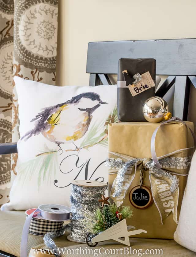 Presents, ribbon and a Noel bird pillow are on the bench.
