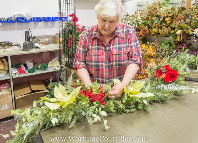 Putting in different types of flowers into the garland.