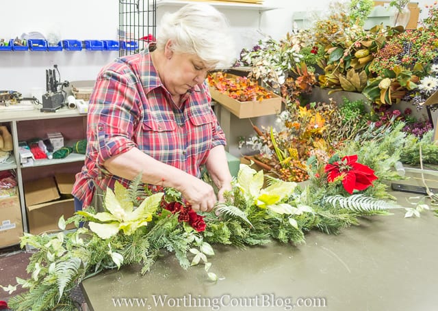 A woman is tucking in all the flowers into the garland.