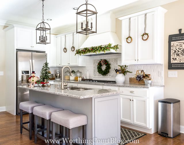 Farmhouse Christmas Kitchen with a wreath hanging above the stove, and mini wreaths on the cabinets.