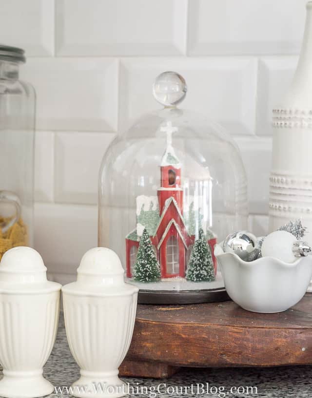 A cloche with a red church figurine underneath it.