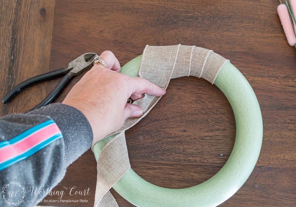 To make a Valentine's Day wreath, start out by wrapping your wreath form with burlap ribbon.