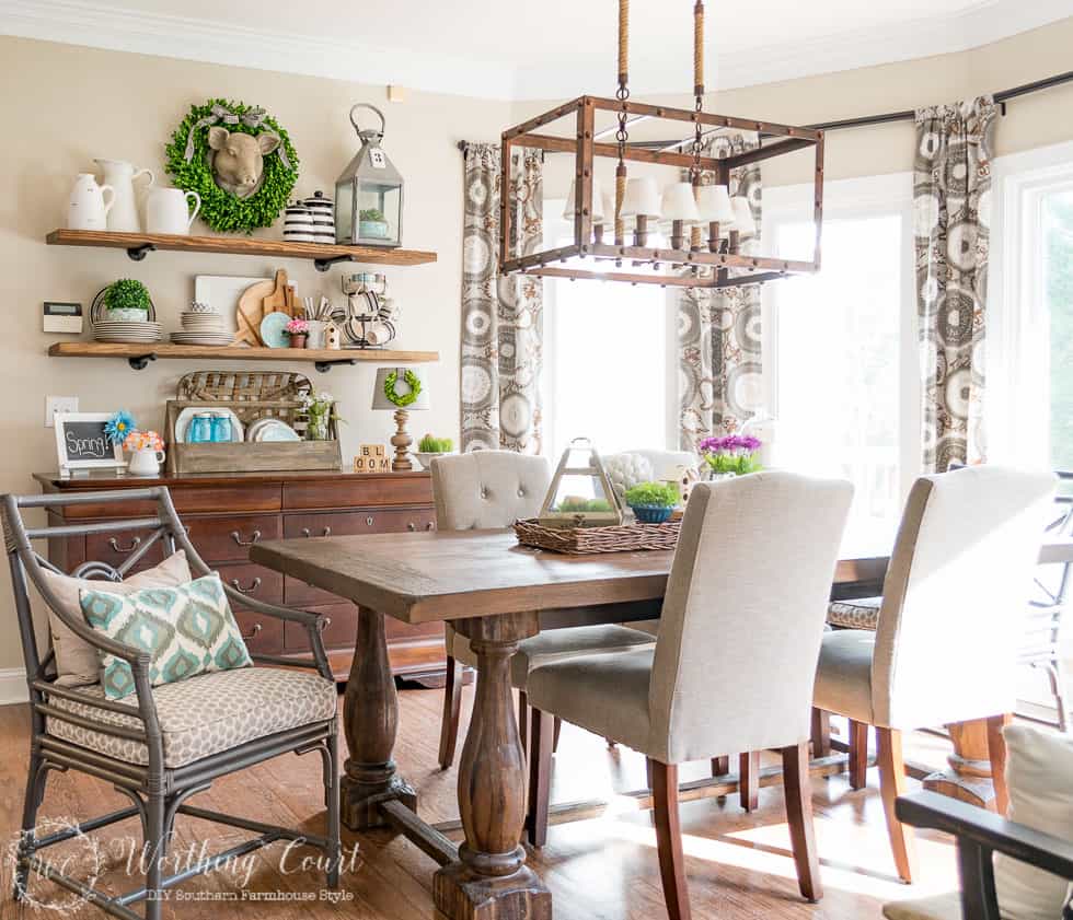 The dining room wooden table, with purple pop of floral color on the table.