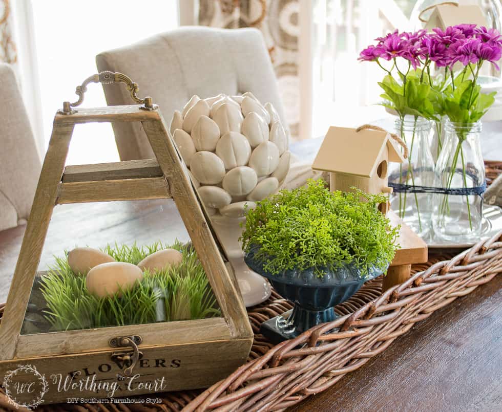 A terrarium filled with faux grass and Easter eggs.