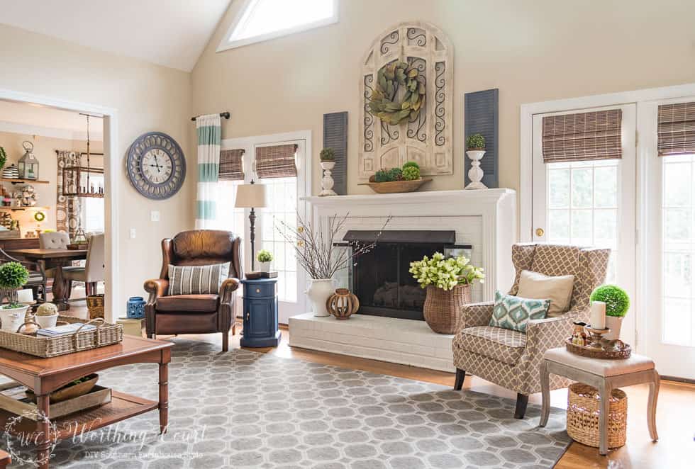 This fireplace celebrates the arrival of spring by filling the mantel and hearth with texture and a mix of real and faux branches and greenery. From a basket overflowing with tulips to an urn filled with pussy willow branches, to a magnolia leaf wreath to an abundance of boxwood orbs, there's no doubt what season it is in this family room.