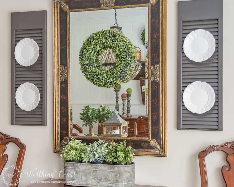There is a bright green wreath hanging from the mirror in the dining room.
