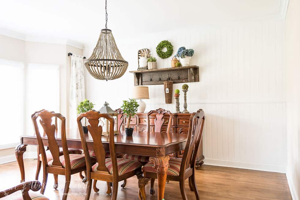 A wooden dining room table with a beaded chandelier above it.
