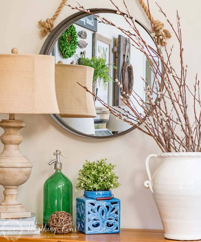 There are spring branches on the mantel beside the mirror.