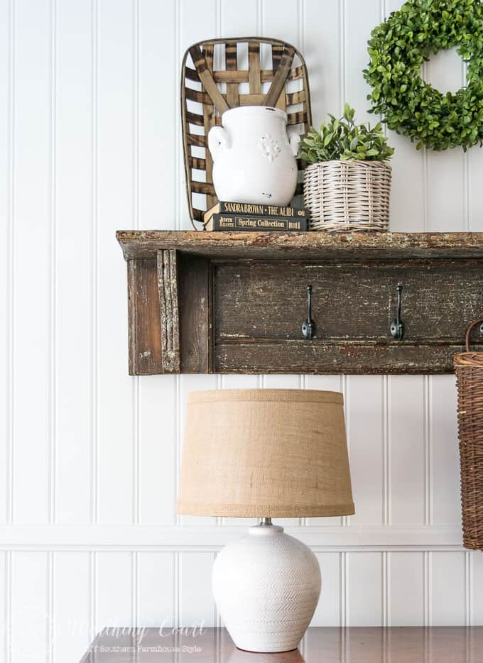 A white planked wall with a wooden shelf.