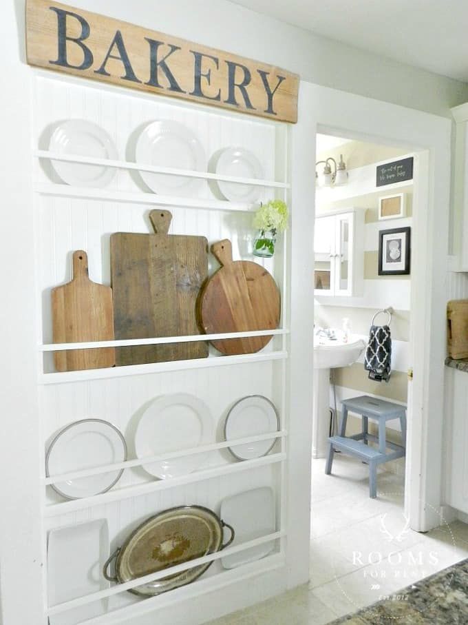 A white plate rack with wooden bread boards and plates on it.