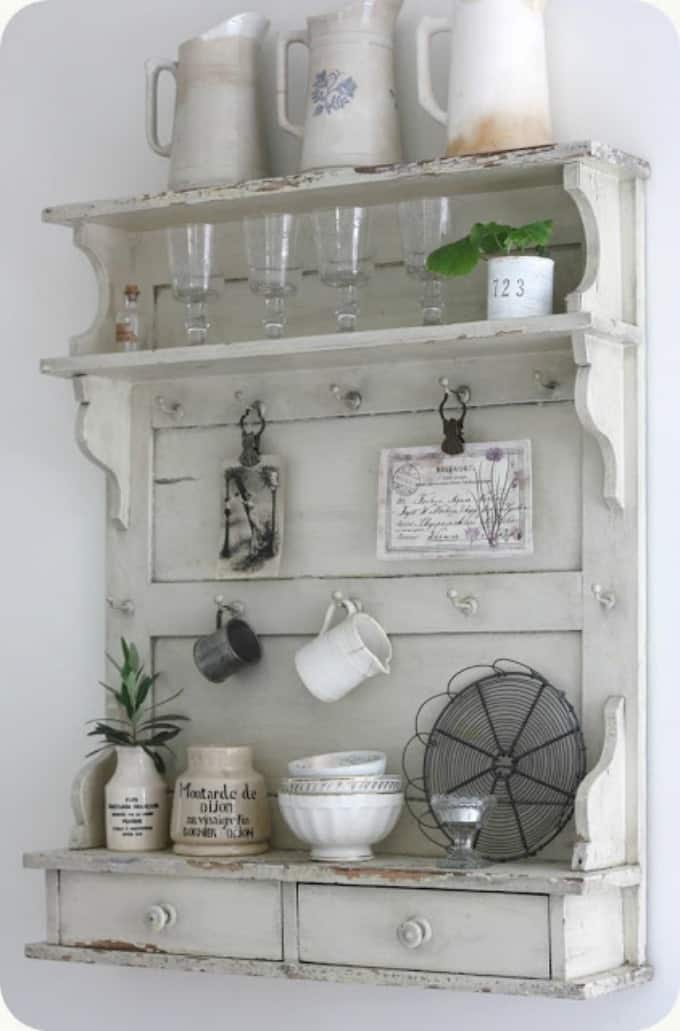 A wooden hutch with pitchers and bowls, glasses on it.