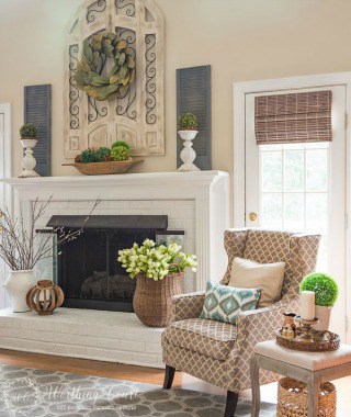 This fireplace celebrates the arrival of spring by filling the mantel and hearth with texture and a mix of real and faux branches and greenery. From a basket overflowing with tulips to an urn filled with pussy willow branches, to a magnolia leaf wreath to an abundance of boxwood orbs, there's no doubt what season it is in this family room.