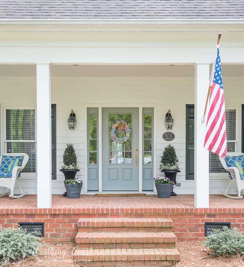 The front porch with planters and rocking chairs plus an American flag.