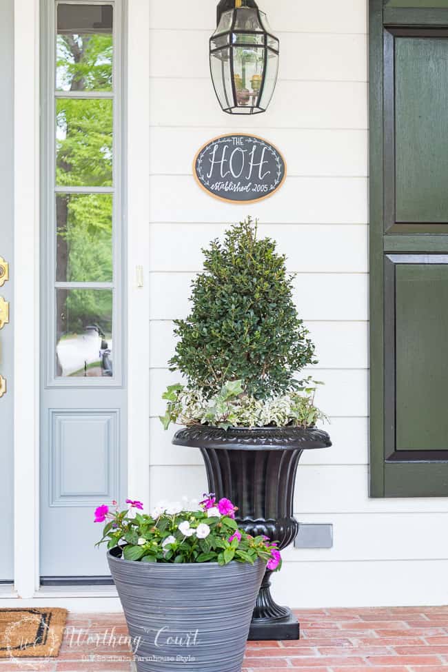 A container full of purple and white flowers on the porch.