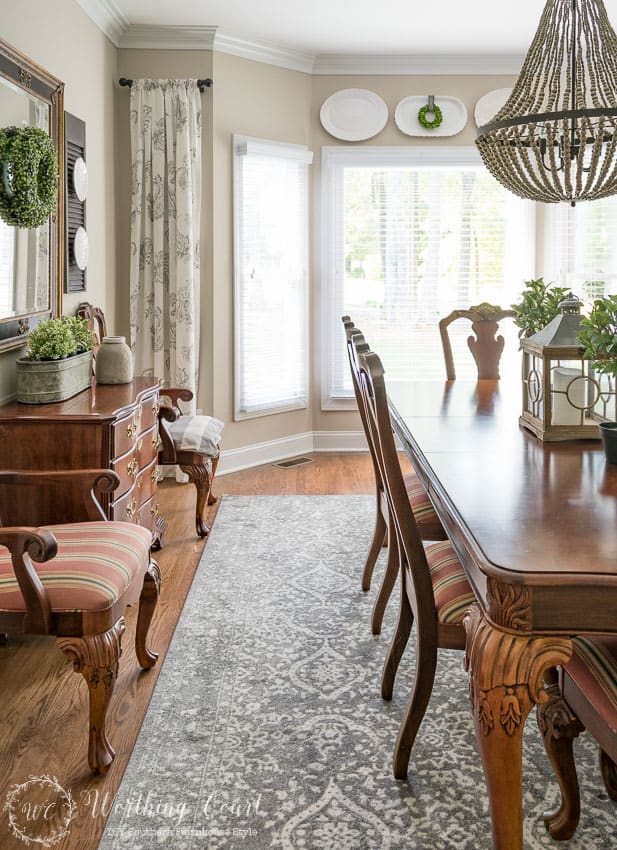 A wooden dining room table and a beaded chandelier over top.