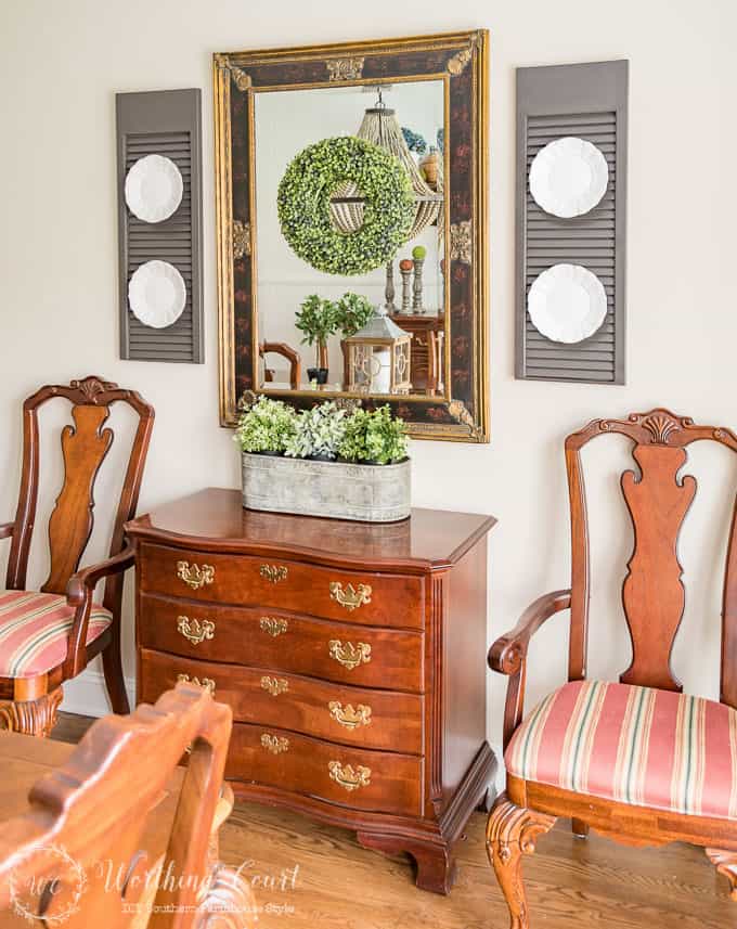 A large mirror on the wall flanked by two shutters.