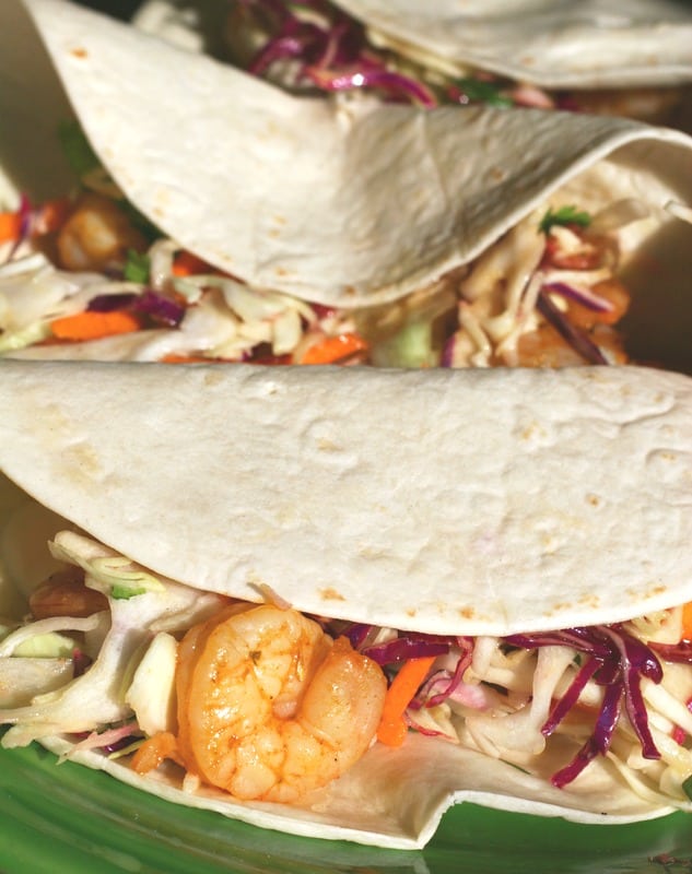 A green plate with an up close picture of the shrimp tacos on it.