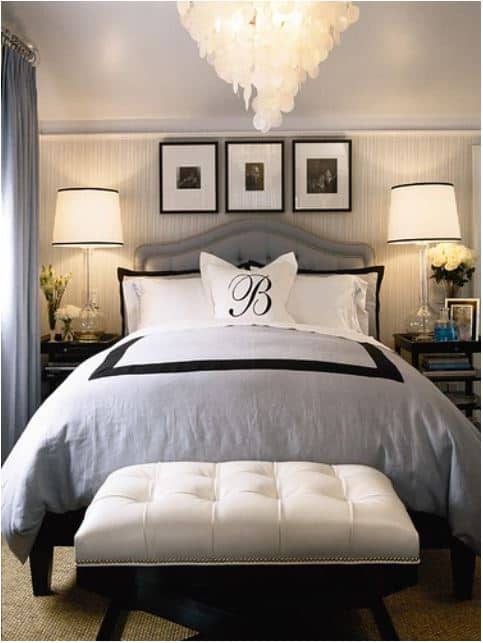 bed with gray, white and black bedding with a bench at the foot of the bed