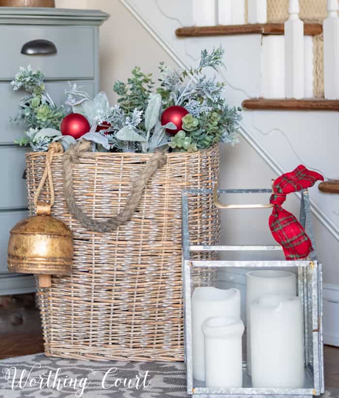 Basket fill with greenery and red Christmas ornaments at the entryway.