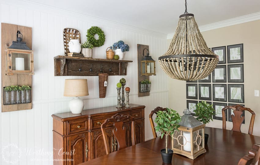 There is a large dining room table with a beaded chandelier over top of it.