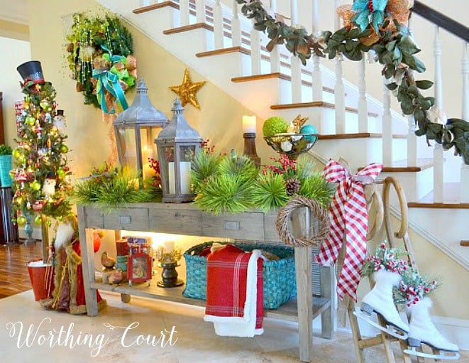 Foyer with Christmas decorations on a sofa table by the stairs.