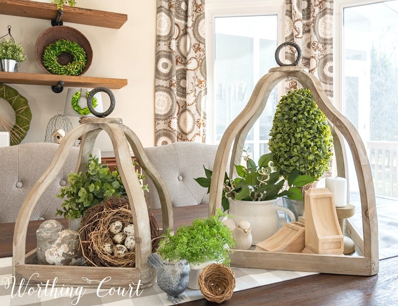 Wood lanterns with greenery inside on the dining room table.