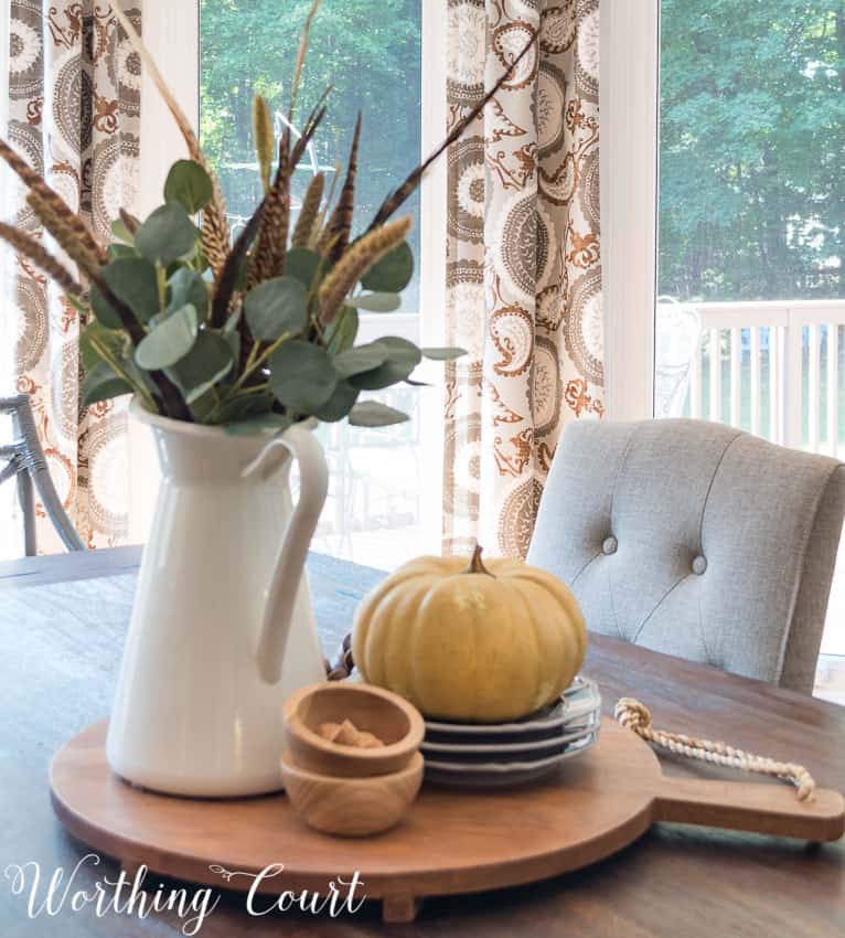 Small wooden bowls are beside the white pitcher on the dining room table.