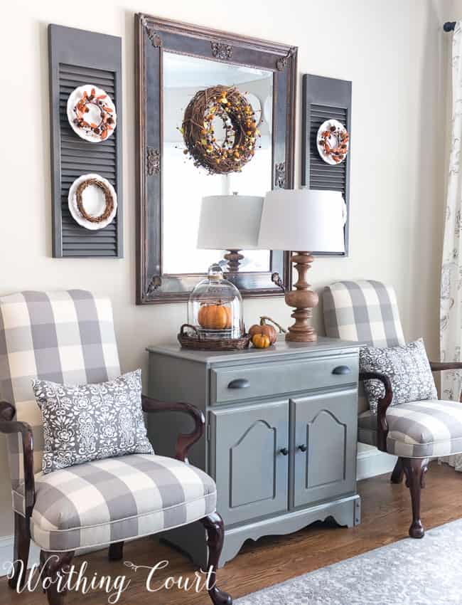 Fall dining room cabinet vignette with a glass cloche and a pumpkin inside the cloche.