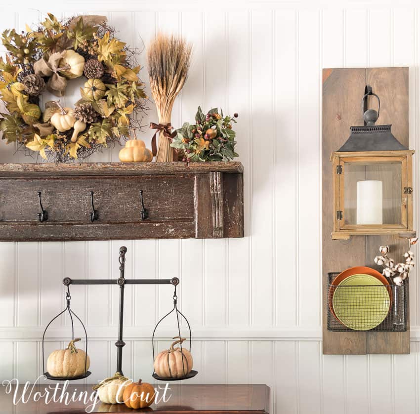 Fixer Upper style hanging lanterns and baskets dressed up for fall and an old fashioned scale with small pumpkins on it.