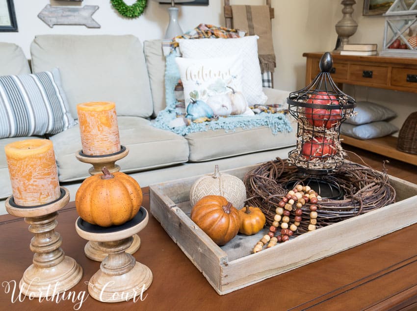 A fall coffee table vignette filled with candles, pumpkins and grapevine wreath.