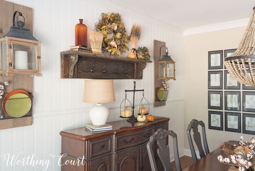 There is a wooden sideboard with fall decor.