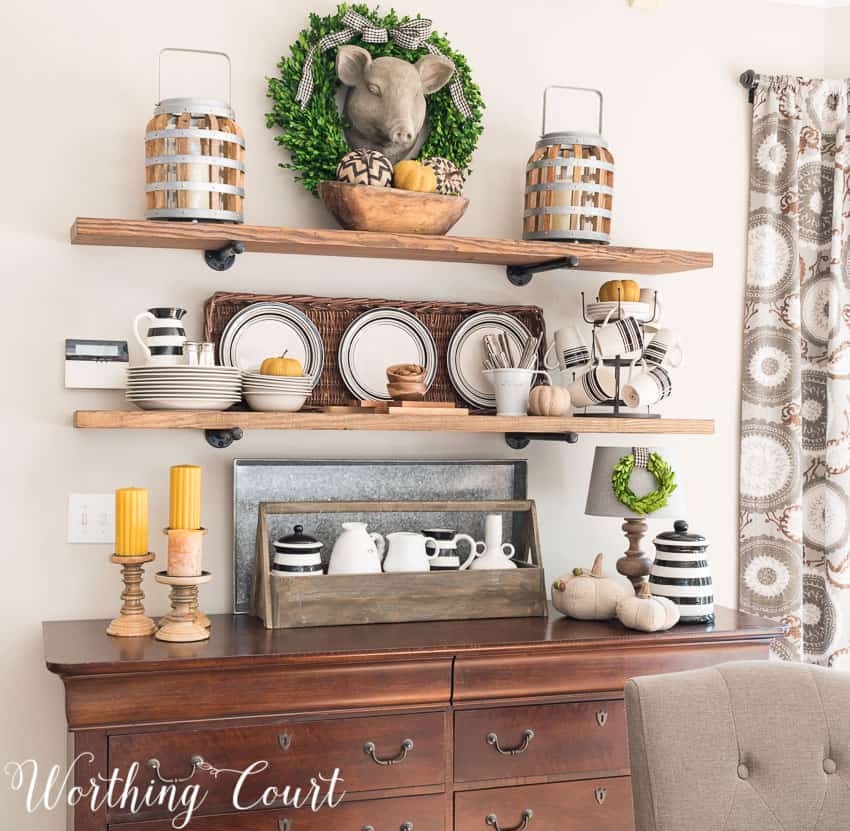 Farmhouse breakfast area open shelves decorated for fall above the wooden hutch.