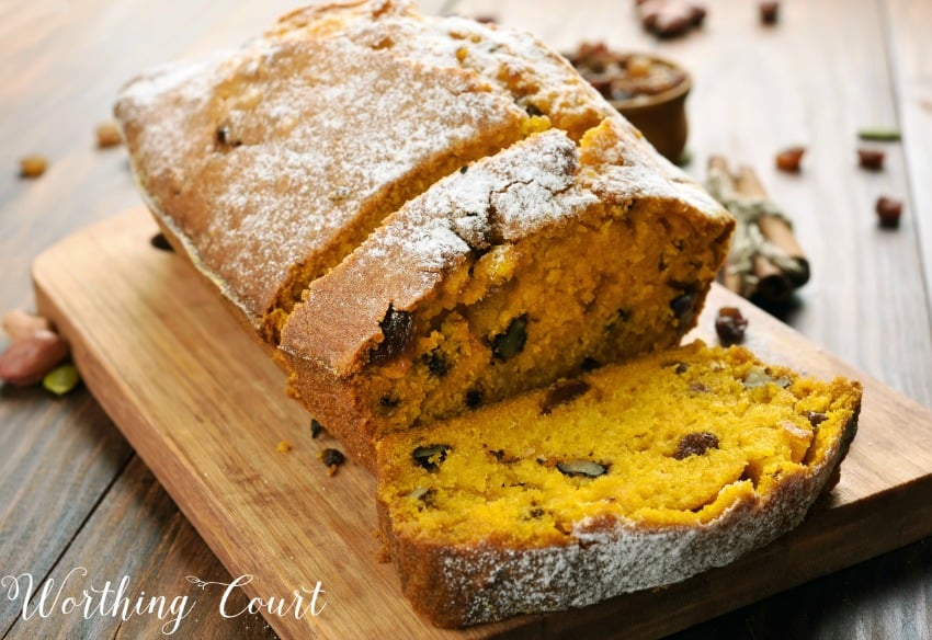 Recipe for the most delicious pumpkin bread you will ever eat with the bread on a wooden cutting board and a slice cut.