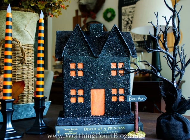 The Halloween house all decorated on a book with orange and black candlesticks.