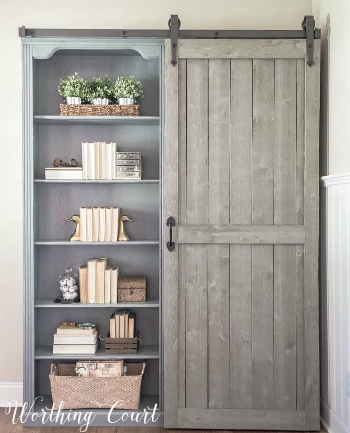 pair of gray bookcases with sliding door on front
