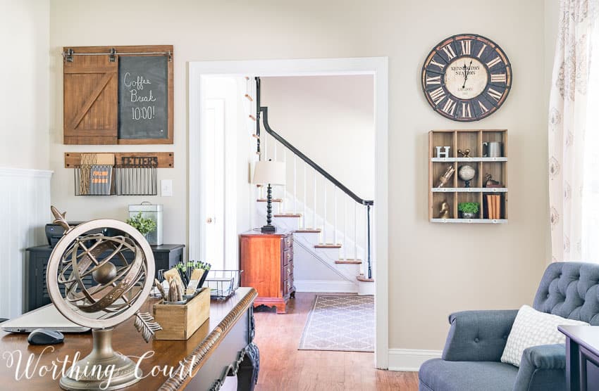 A home office with a globe on the desk, a blue armchair and rustic industrial decor on the wall.