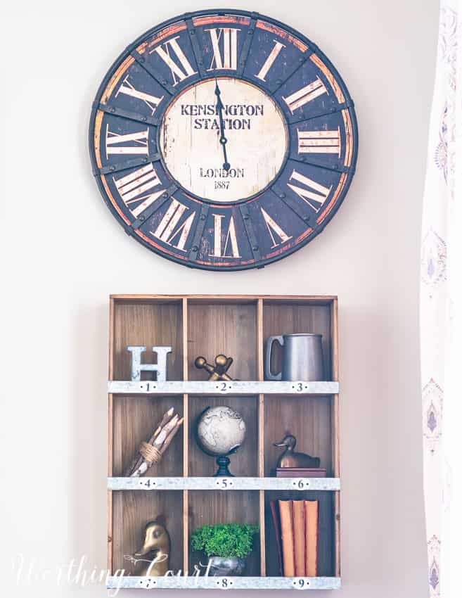 A rustic clock and wooden wall cubby filled with decor items.