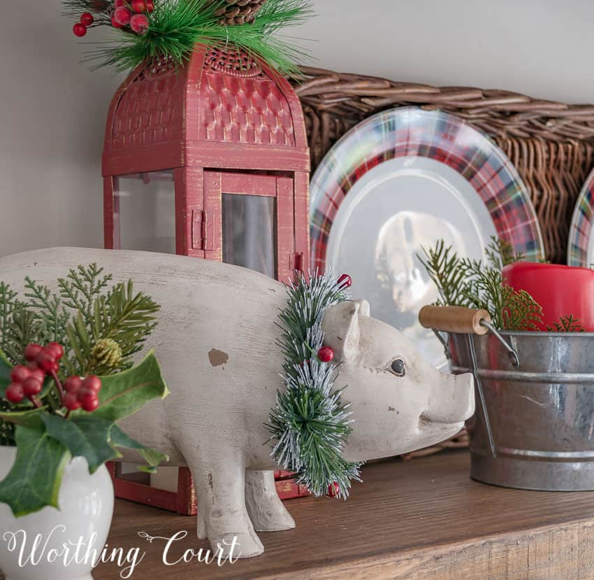 A ceramic pig with a wreath around its neck is on the open shelving unit.