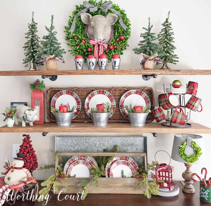 Open rustic shelves decorated for Christmas using plaid dishes.