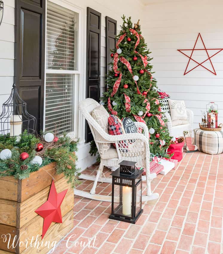 Front porch Christmas tree decorated with red ribbon.