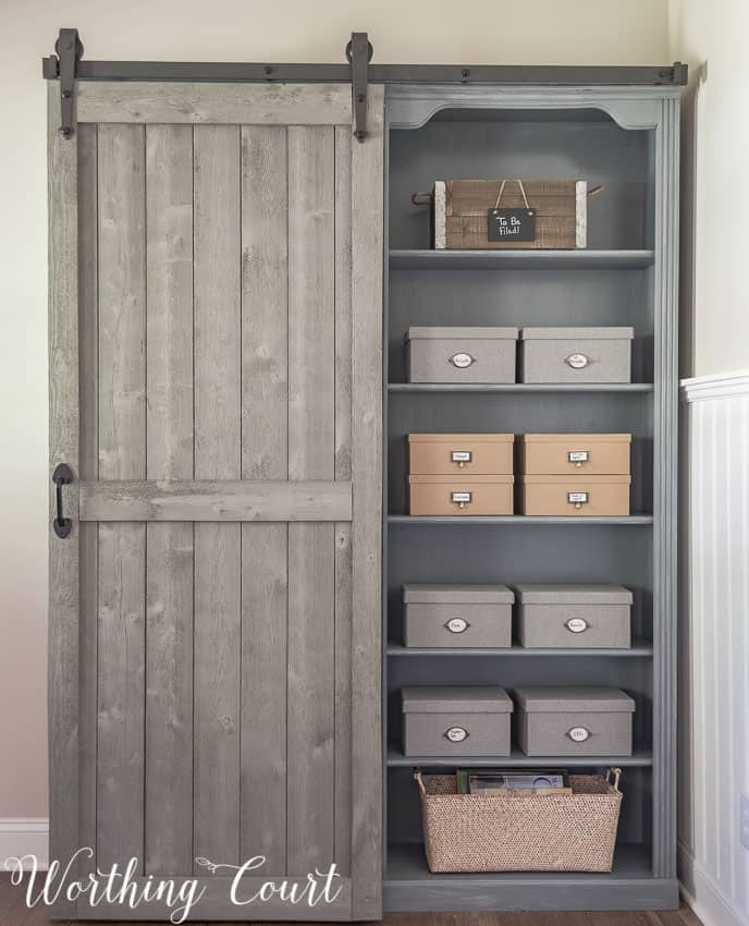 Hidden storage behind a diy sliding barn door on bookcases.