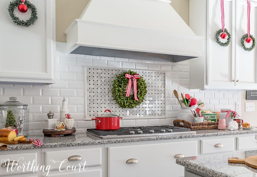 Christmas wreath with red and white striped ribbon above the cooktop.