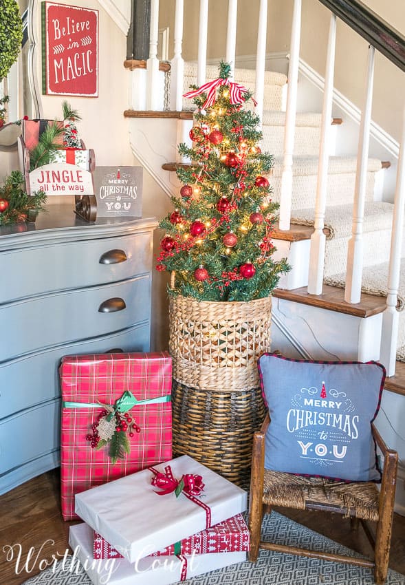 Small Christmas tree for a foyer with presents underneath it.