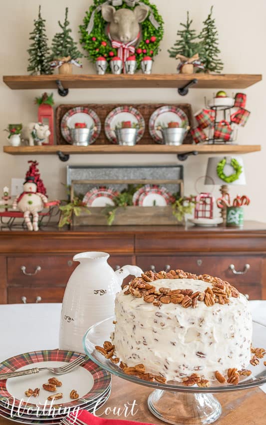 The red velvet cake is on the table with decorated open shelves behind it.