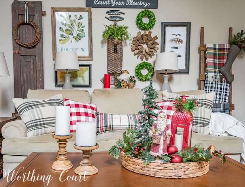 A small tray with a holiday vignette in it, plus white candles beside it.