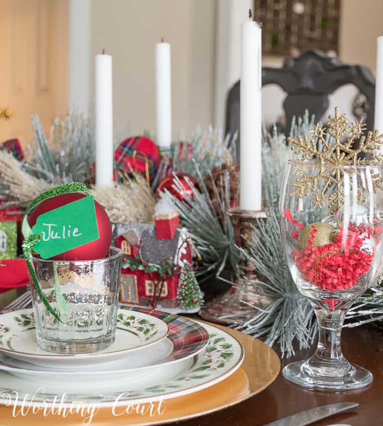 A wine glass filled with a gold snow flake and gold ornament.