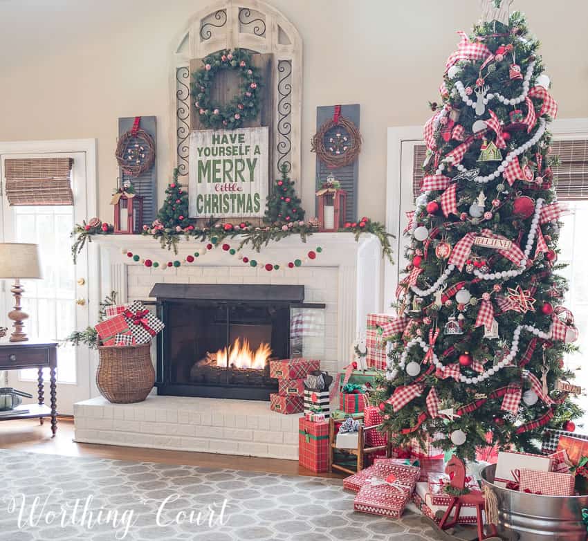 A large Christmas tree beside the lit fireplace in the family room.